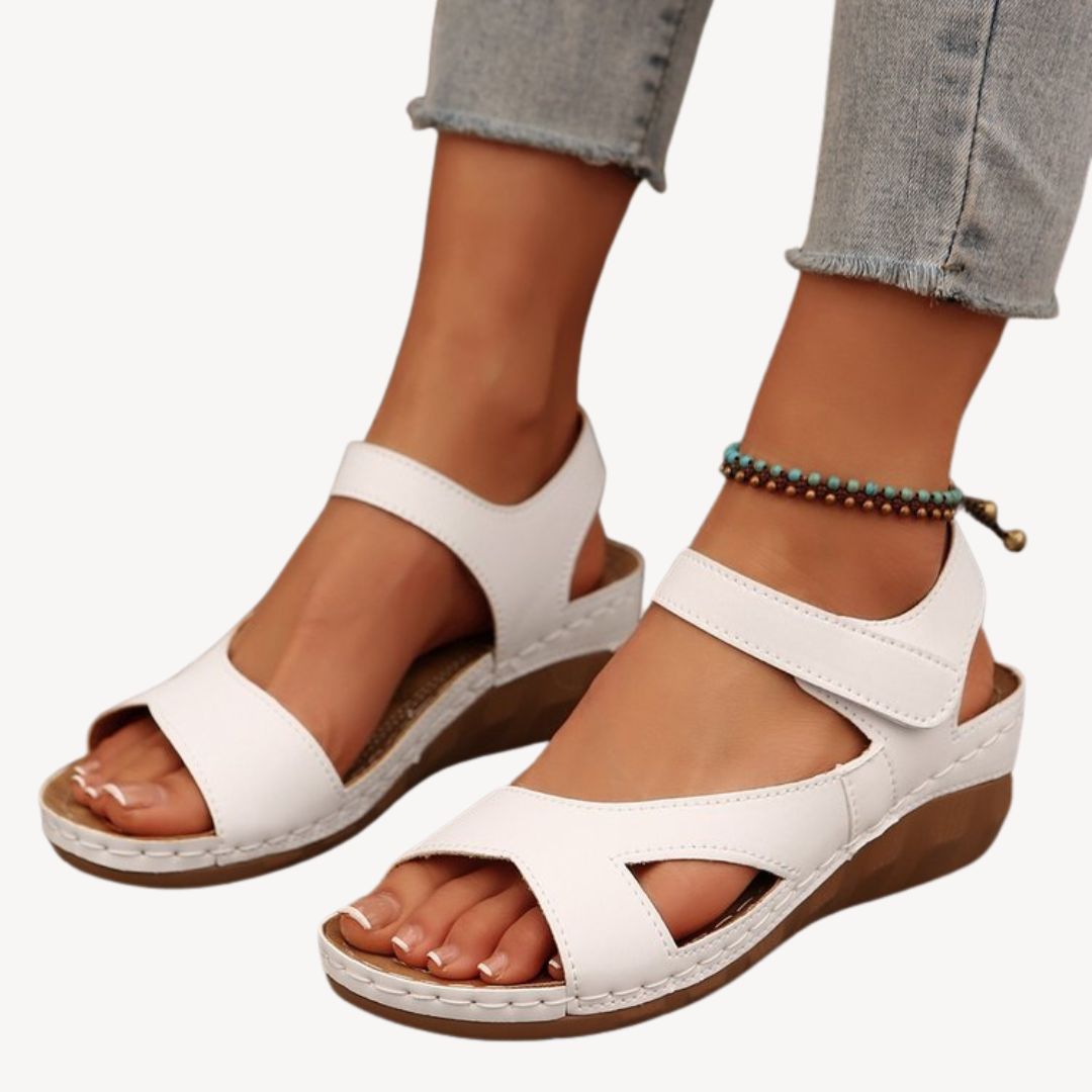 Black women's leather orthopedic sandals with adjustable Velcro straps, low wedge heel, and flexible sole for comfort.