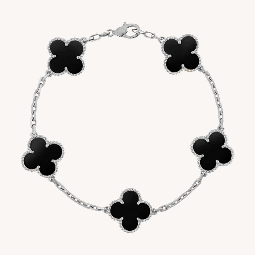 Elegant clover charm bracelet with polished black agate inlays and a gold and silver-tone chain for sophisticated style.