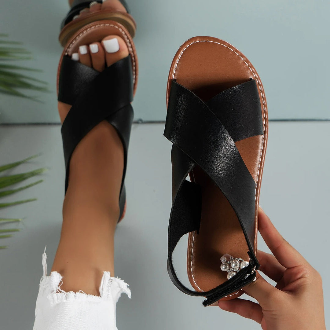 "Elegant women's leather buckle sandals with flat sole, featuring an adjustable strap, available in black and brown."
