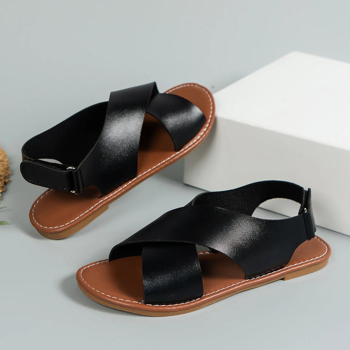 "Elegant women's leather buckle sandals with flat sole, featuring an adjustable strap, available in black and brown."