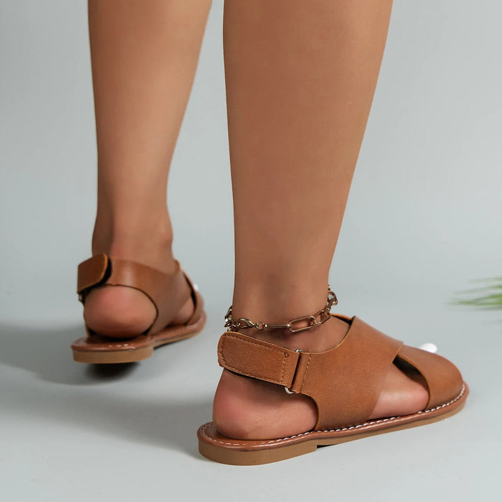 "Elegant women's leather buckle sandals with flat sole, featuring an adjustable strap, available in black and brown."