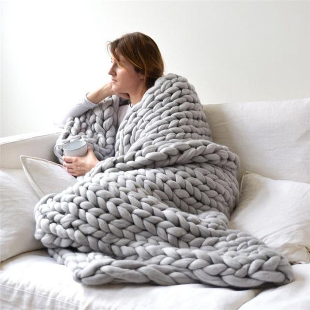 "Handmade chunky knit blanket, super soft texture, vibrant colors draped on furniture, decorative and cozy home accent."
