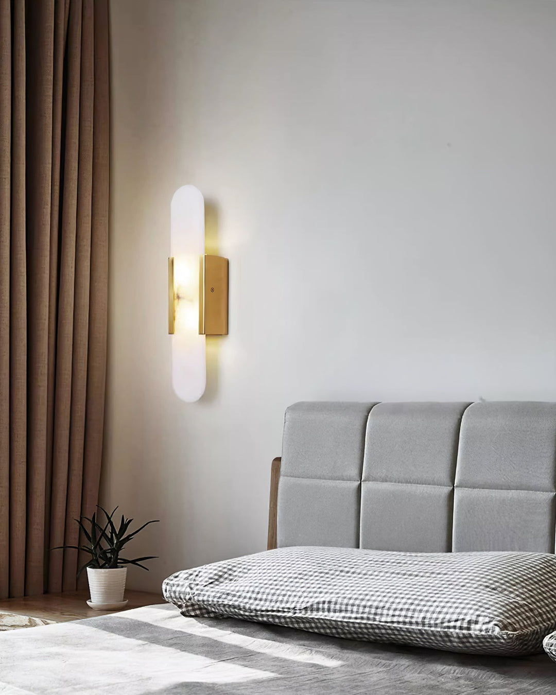 "Modern elongated alabaster wall lamp with metal and brass accents, emits warm glow, suitable for chic interior decor."
