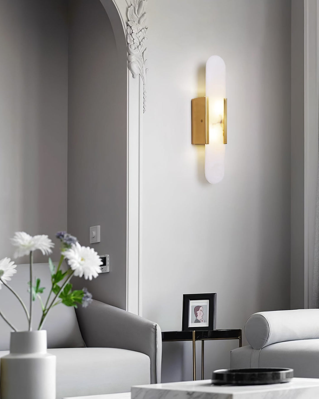 "Modern elongated alabaster wall lamp with metal and brass accents, emits warm glow, suitable for chic interior decor."