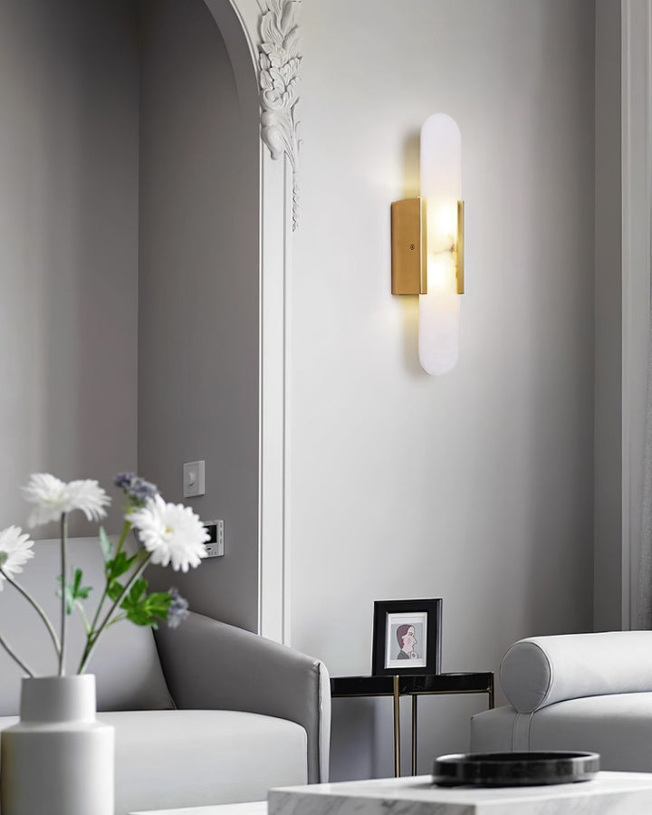 "Modern elongated alabaster wall lamp with metal and brass accents, emits warm glow, suitable for chic interior decor."
