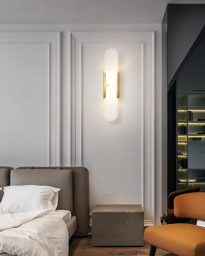"Modern elongated alabaster wall lamp with metal and brass accents, emits warm glow, suitable for chic interior decor."