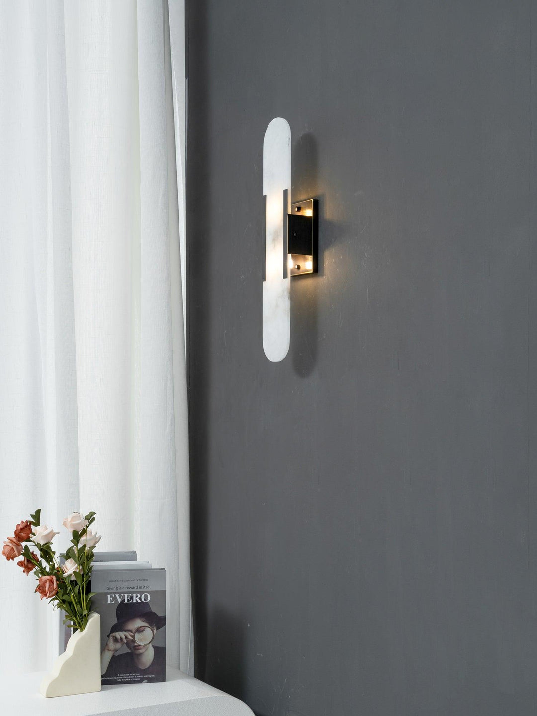 "Modern elongated alabaster wall lamp with metal and brass accents, emits warm glow, suitable for chic interior decor."