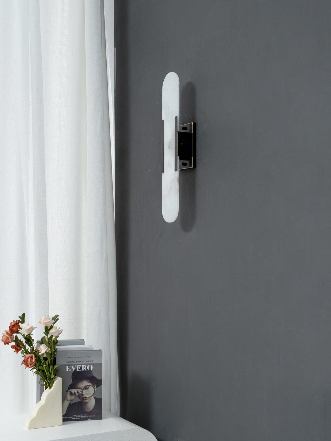 "Modern elongated alabaster wall lamp with metal and brass accents, emits warm glow, suitable for chic interior decor."