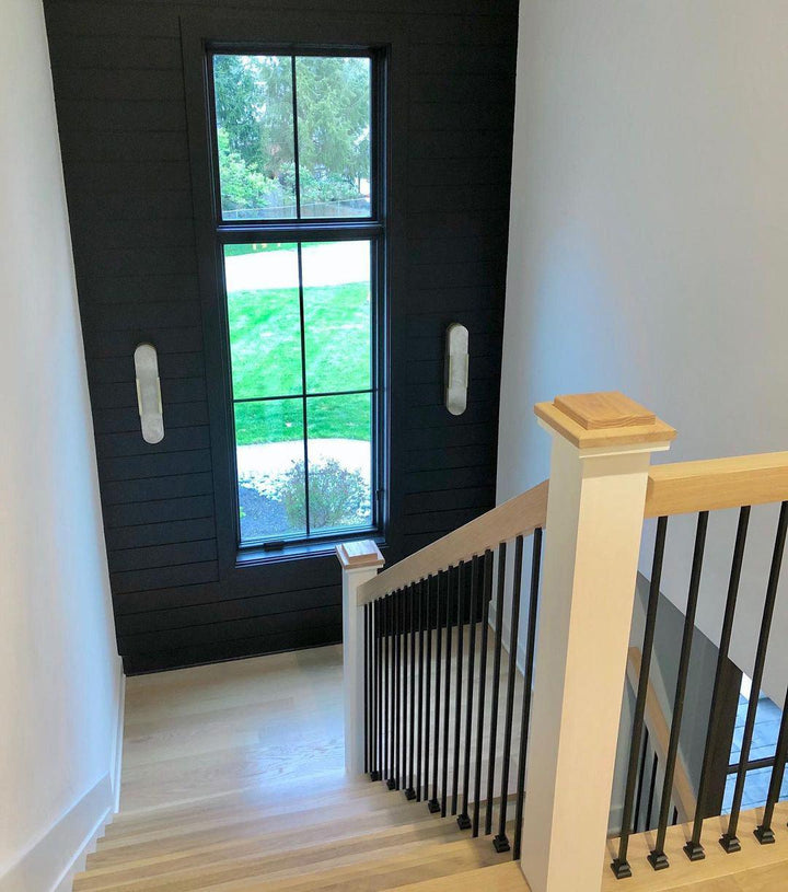 "Modern elongated alabaster wall lamp with metal and brass accents, emits warm glow, suitable for chic interior decor."