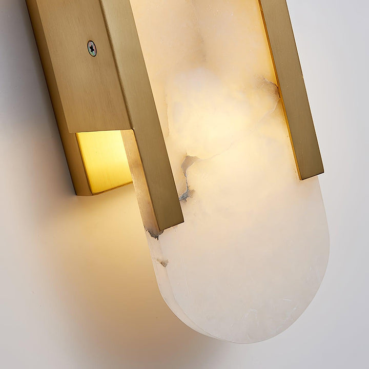 "Modern elongated alabaster wall lamp with metal and brass accents, emits warm glow, suitable for chic interior decor."