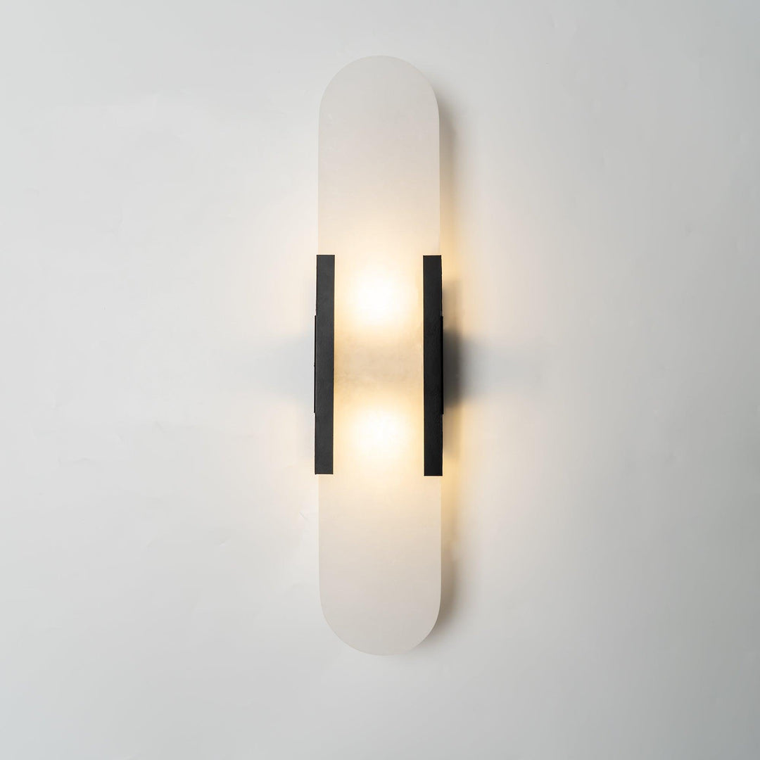 "Modern elongated alabaster wall lamp with metal and brass accents, emits warm glow, suitable for chic interior decor."