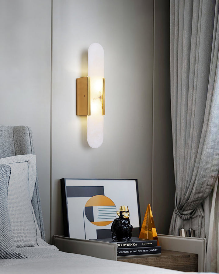 "Modern elongated alabaster wall lamp with metal and brass accents, emits warm glow, suitable for chic interior decor."
