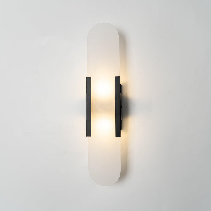 "Modern elongated alabaster wall lamp with metal and brass accents, emits warm glow, suitable for chic interior decor."