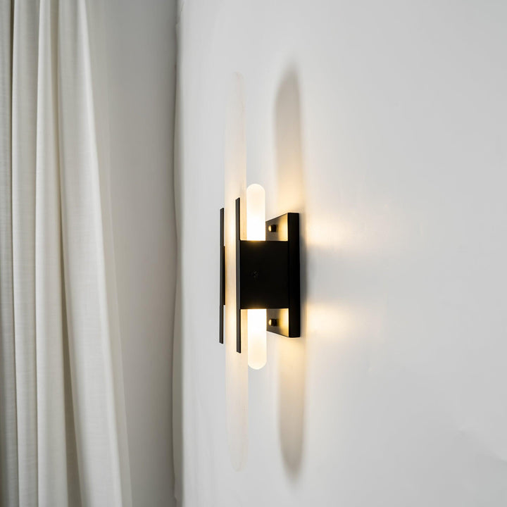 "Modern elongated alabaster wall lamp with metal and brass accents, emits warm glow, suitable for chic interior decor."