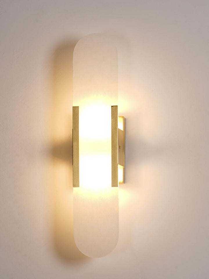 "Modern elongated alabaster wall lamp with metal and brass accents, emits warm glow, suitable for chic interior decor."