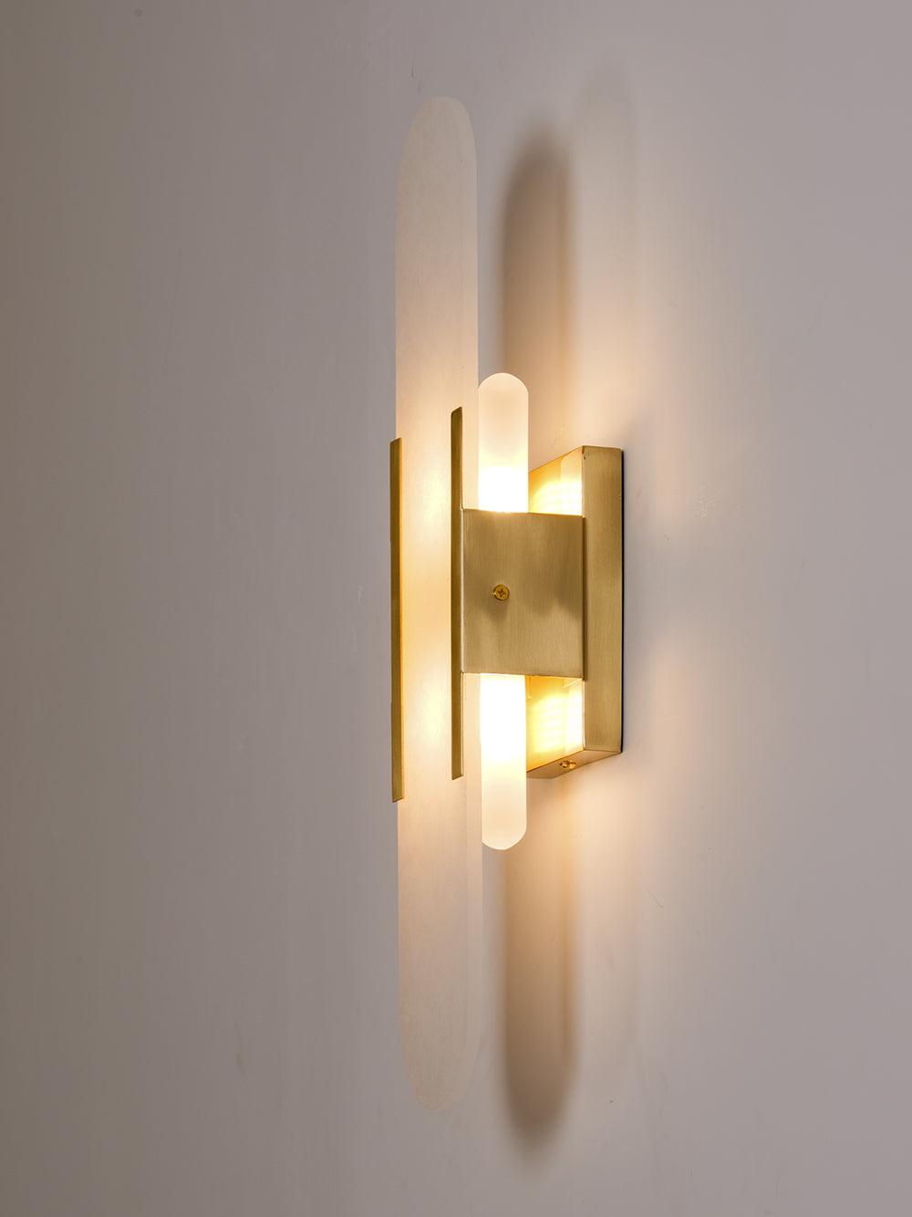"Modern elongated alabaster wall lamp with metal and brass accents, emits warm glow, suitable for chic interior decor."