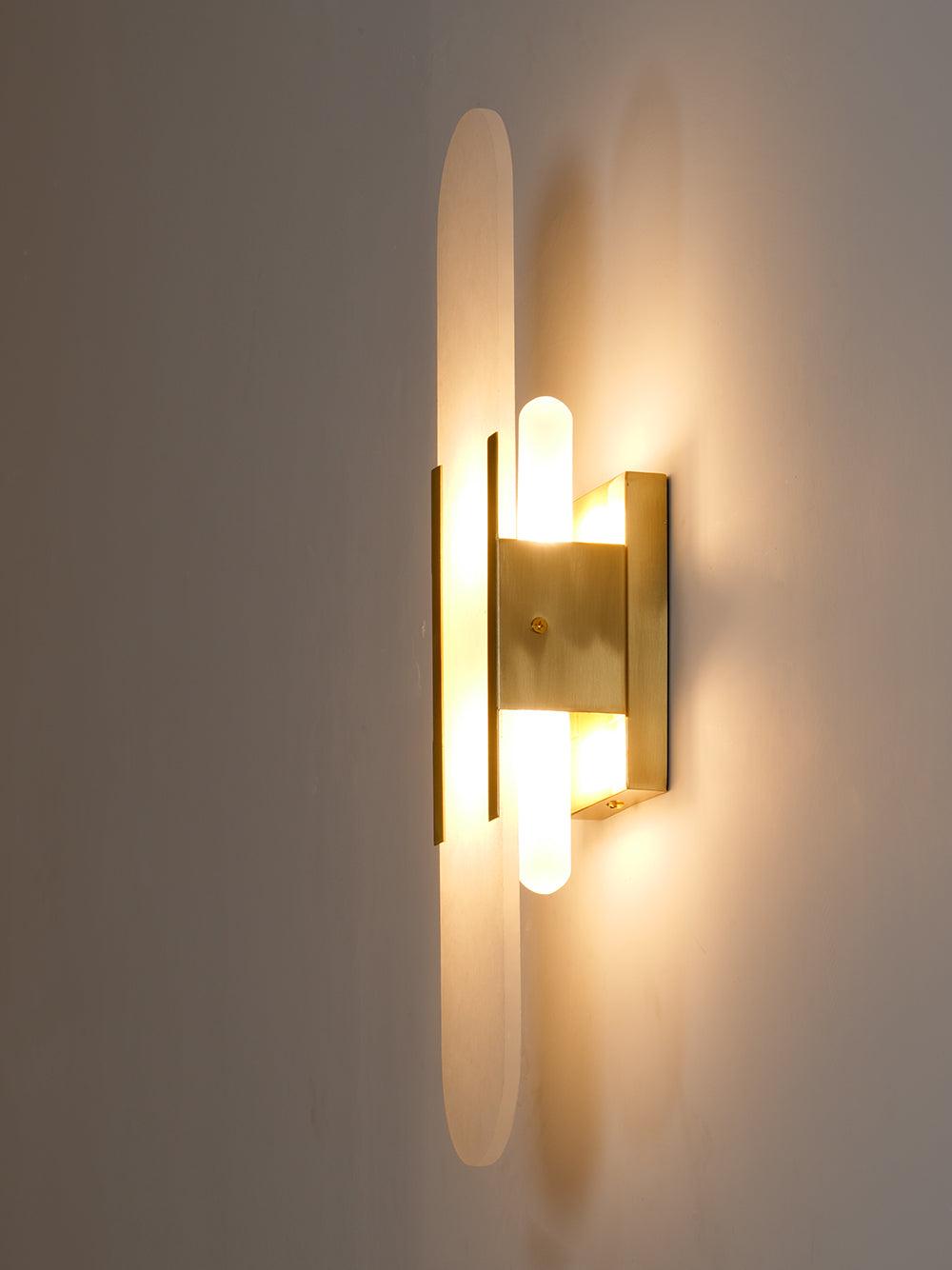 "Modern elongated alabaster wall lamp with metal and brass accents, emits warm glow, suitable for chic interior decor."
