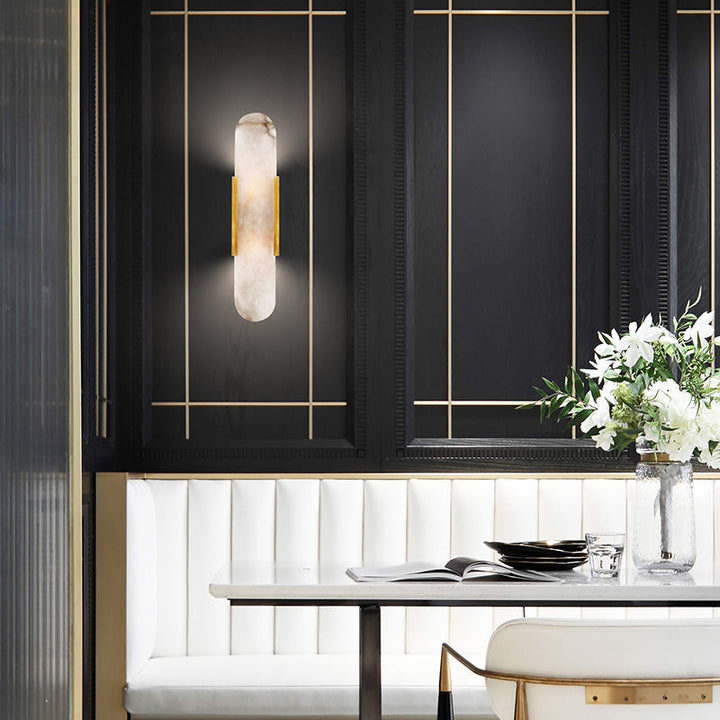 "Modern elongated alabaster wall lamp with metal and brass accents, emits warm glow, suitable for chic interior decor."