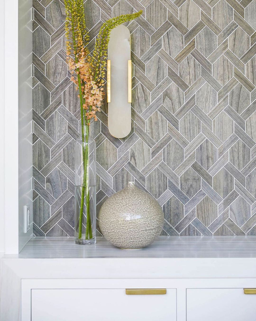 "Modern elongated alabaster wall lamp with metal and brass accents, emits warm glow, suitable for chic interior decor."