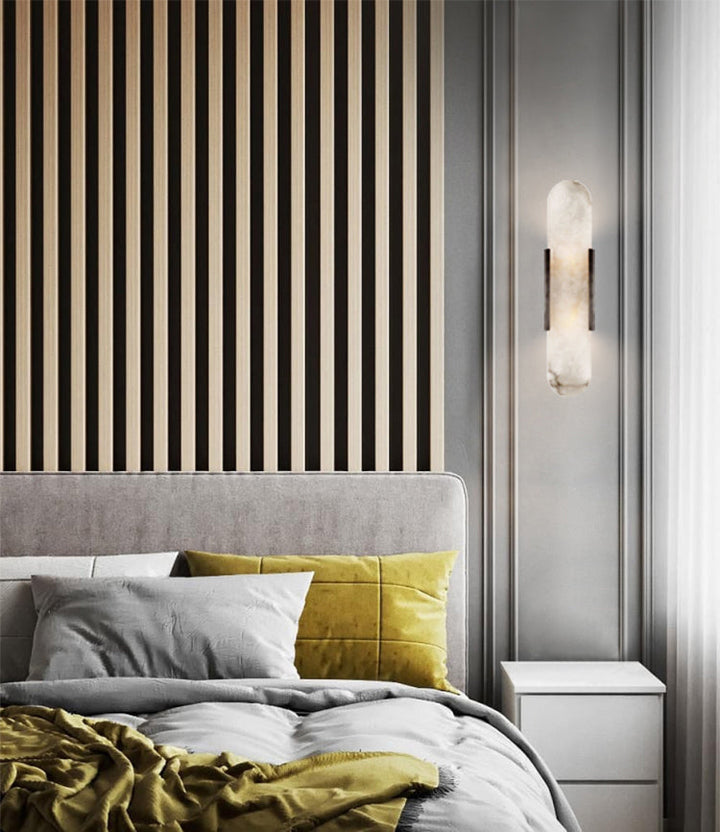 "Modern elongated alabaster wall lamp with metal and brass accents, emits warm glow, suitable for chic interior decor."