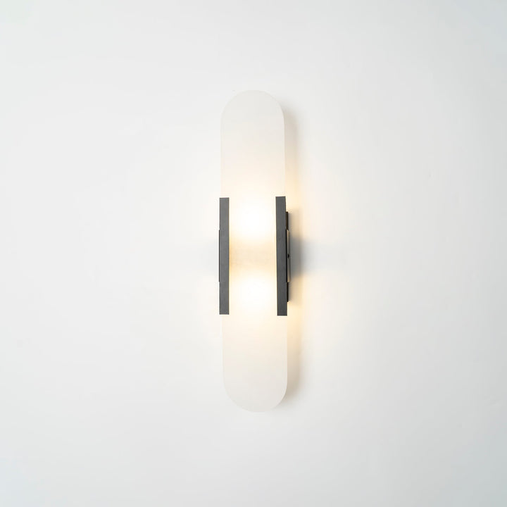 "Modern elongated alabaster wall lamp with metal and brass accents, emits warm glow, suitable for chic interior decor."