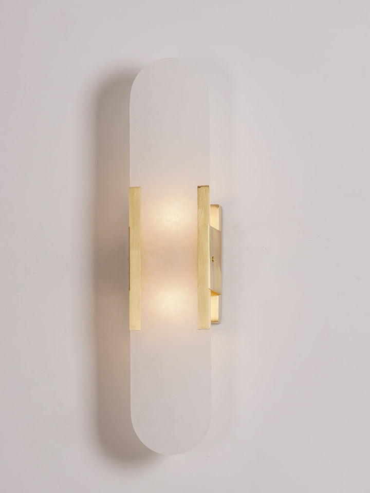 "Modern elongated alabaster wall lamp with metal and brass accents, emits warm glow, suitable for chic interior decor."