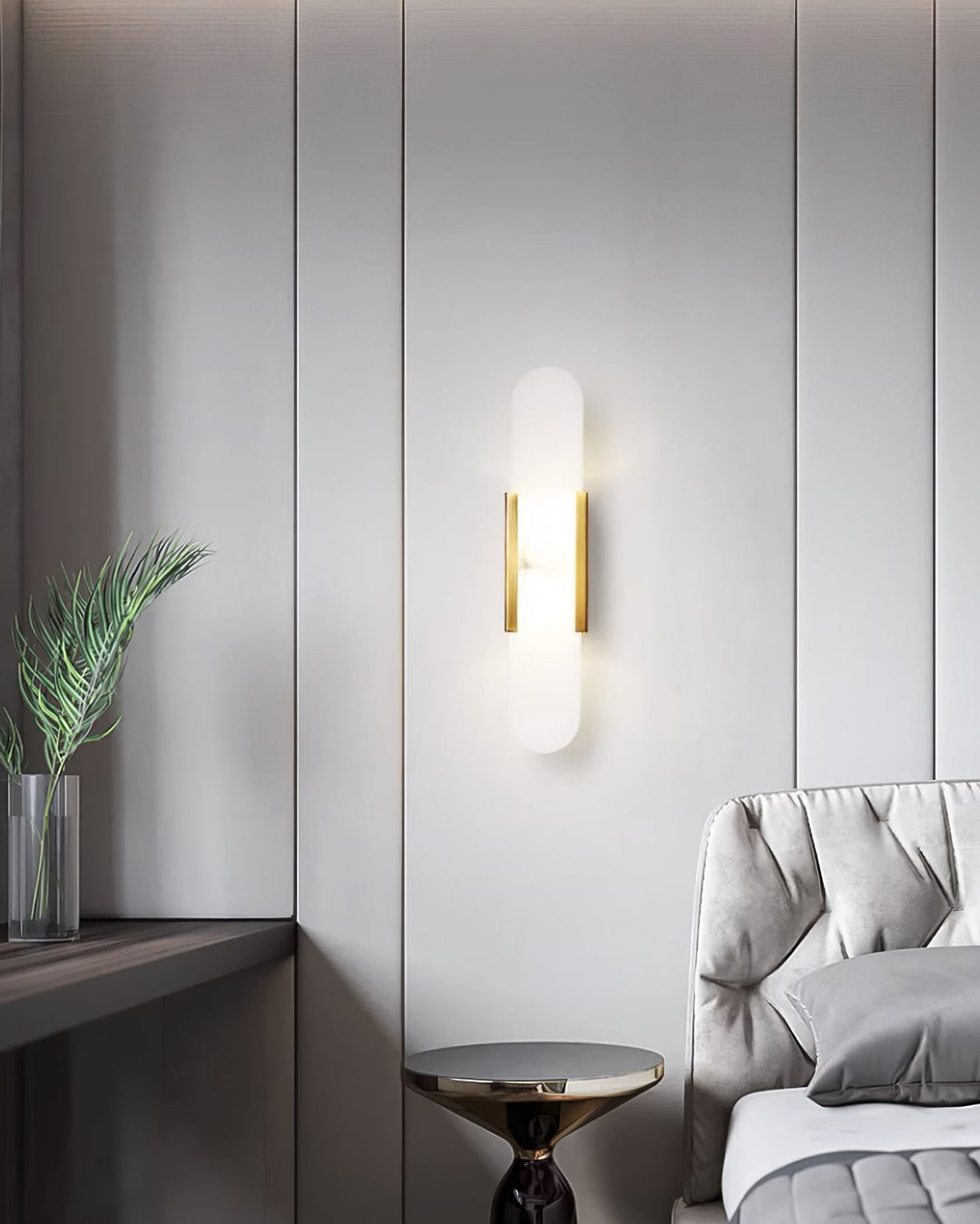 "Modern elongated alabaster wall lamp with metal and brass accents, emits warm glow, suitable for chic interior decor."