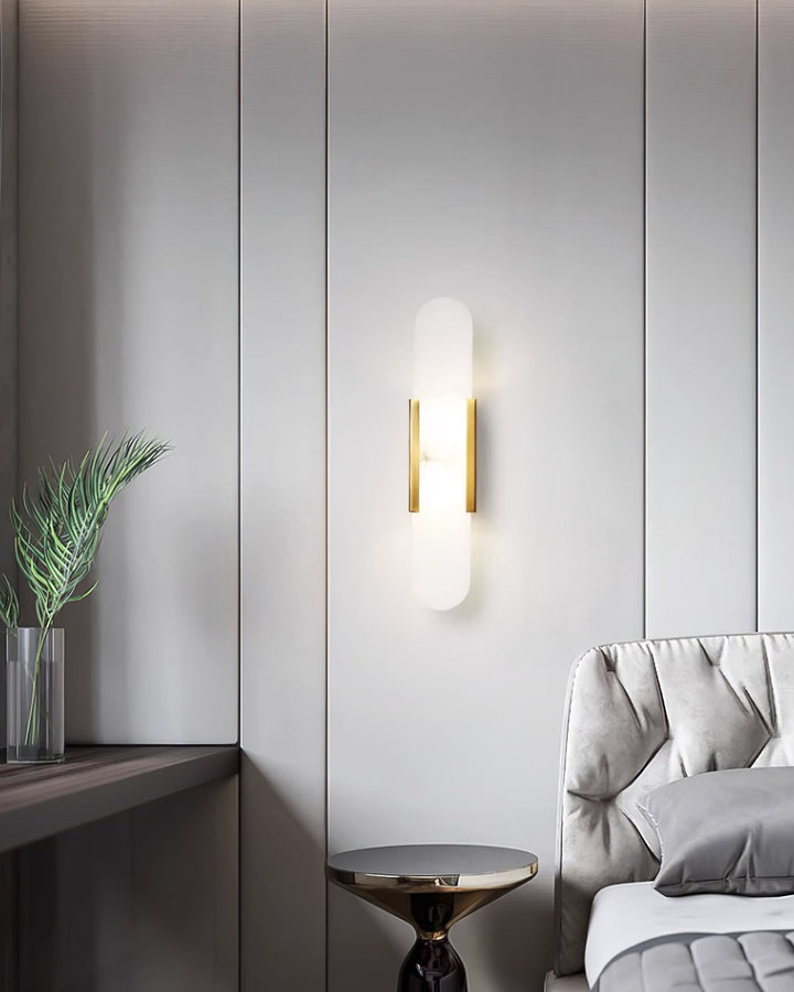 "Modern elongated alabaster wall lamp with metal and brass accents, emits warm glow, suitable for chic interior decor."