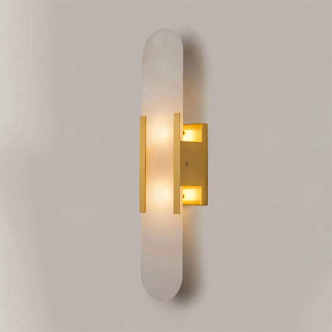 "Modern elongated alabaster wall lamp with metal and brass accents, emits warm glow, suitable for chic interior decor."