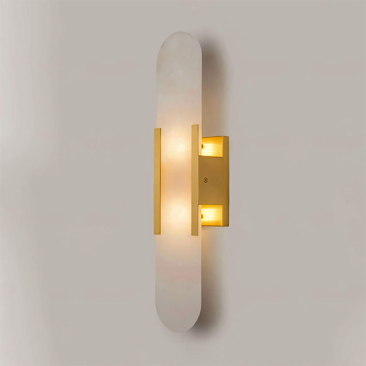"Modern elongated alabaster wall lamp with metal and brass accents, emits warm glow, suitable for chic interior decor."