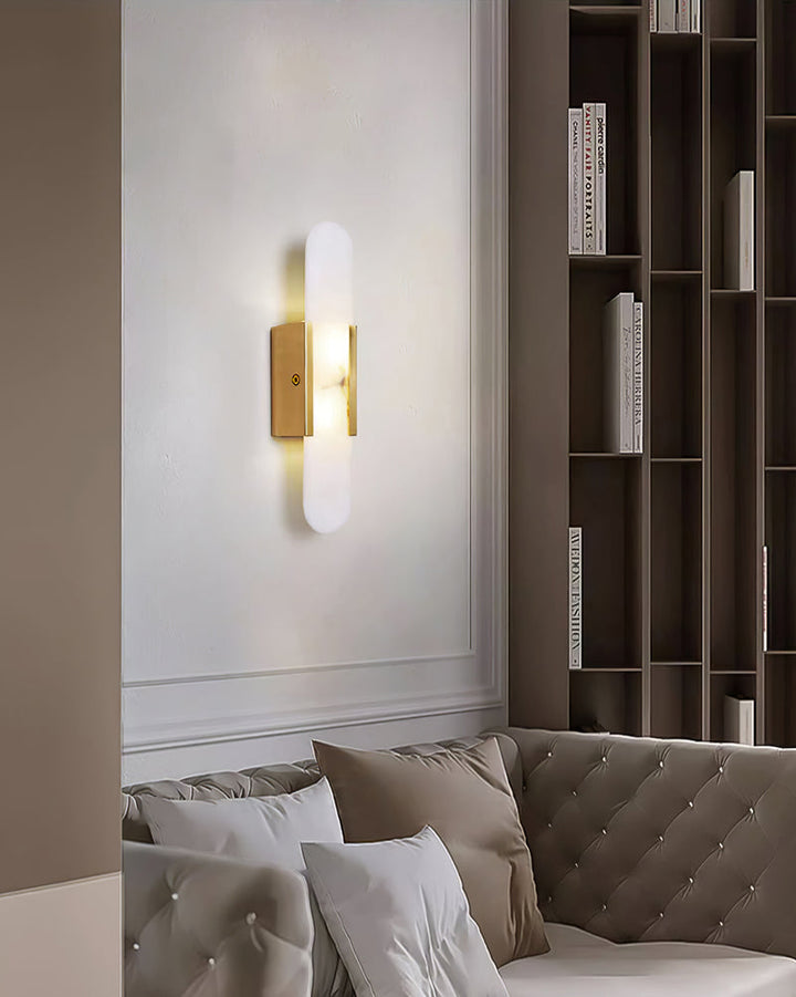 "Modern elongated alabaster wall lamp with metal and brass accents, emits warm glow, suitable for chic interior decor."