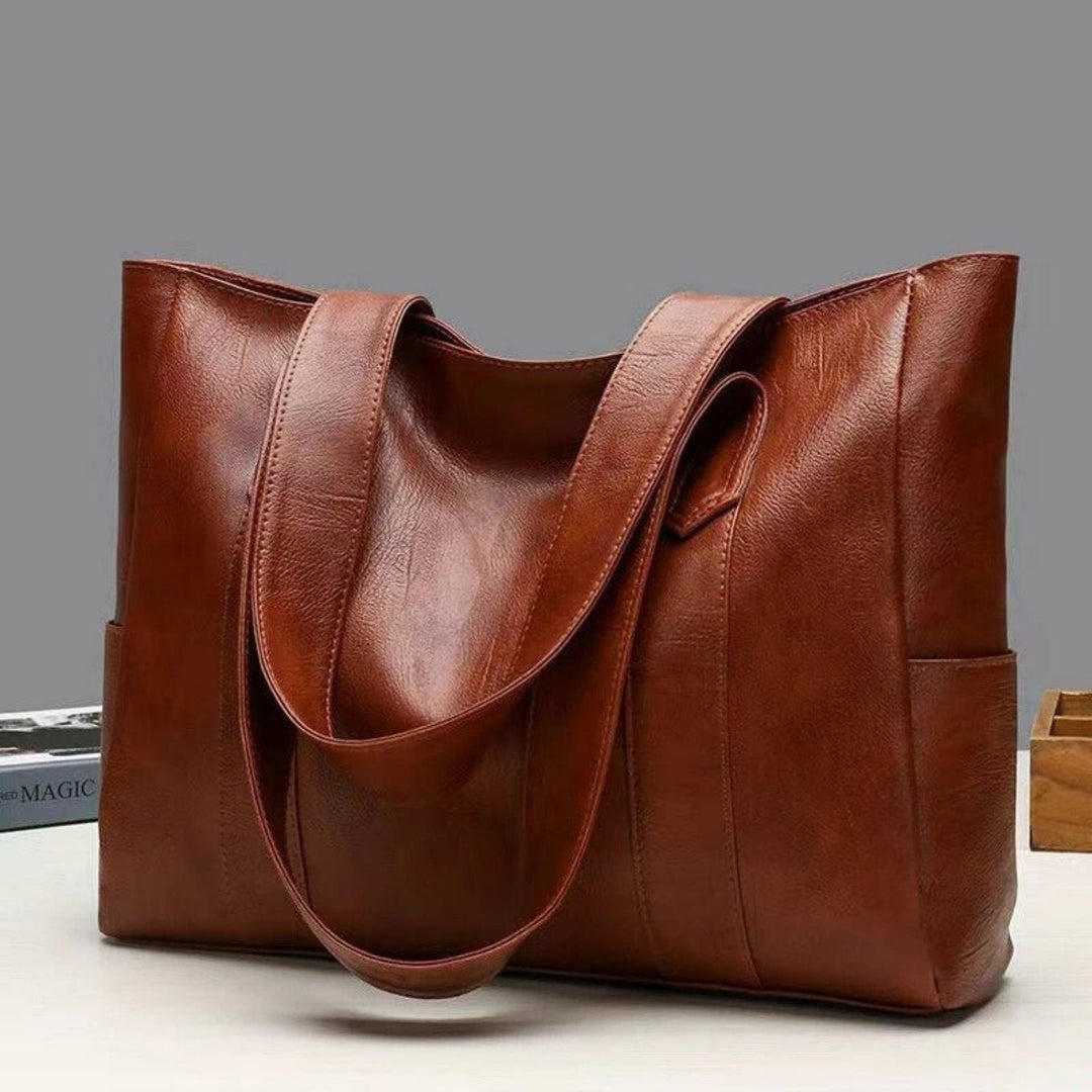 Women's leather tote bag with spacious side pockets, durable leather craftsmanship, elegant design for work or travel.