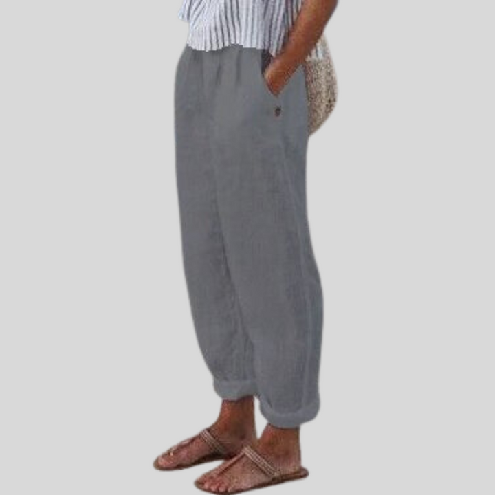 "Women's linen trousers with folded hem, relaxed fit; lightweight, breathable fabric, beige tones, tailored style."