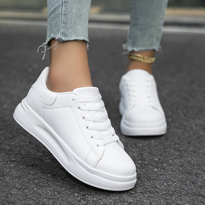 "Women's minimalist white leather sneakers with sleek design and cushioned soles, ideal for casual wear and comfort."