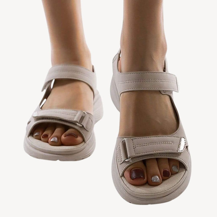 "Beige orthopedic sandals with adjustable straps and arch support, featuring a cushioned shock-absorbing sole."