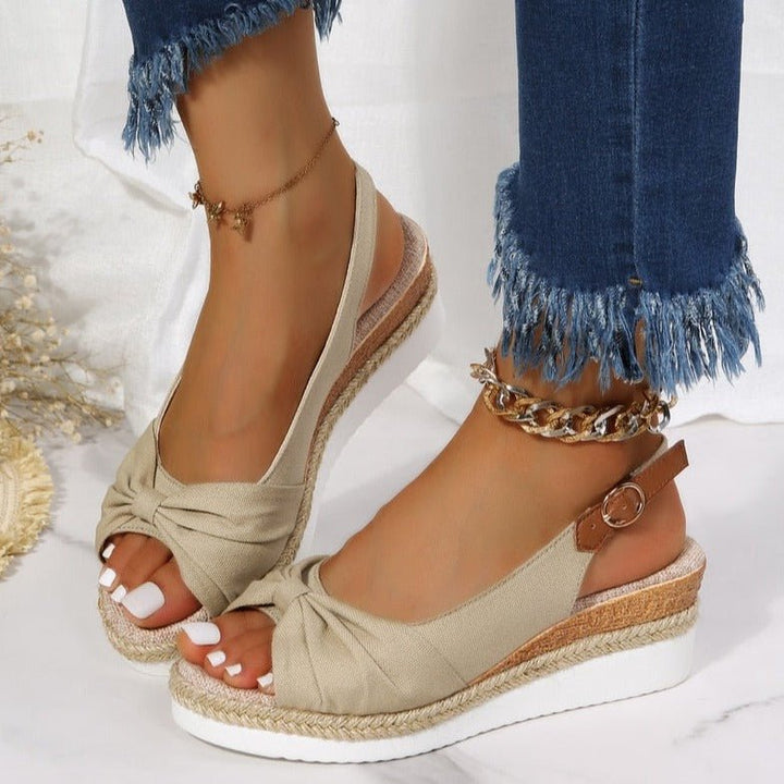 Beige women's wedge sandals with chic knot detail, open toe, slingback strap, and braided jute platform for summer style.