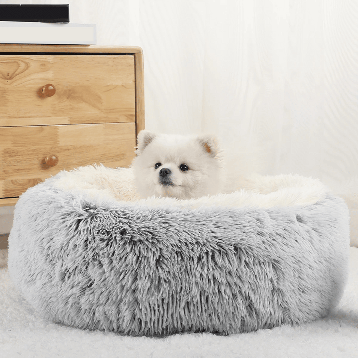 "Cozy plush donut dog bed with deep sides, faux fur, circular shape for comfort and anxiety relief in various sizes."