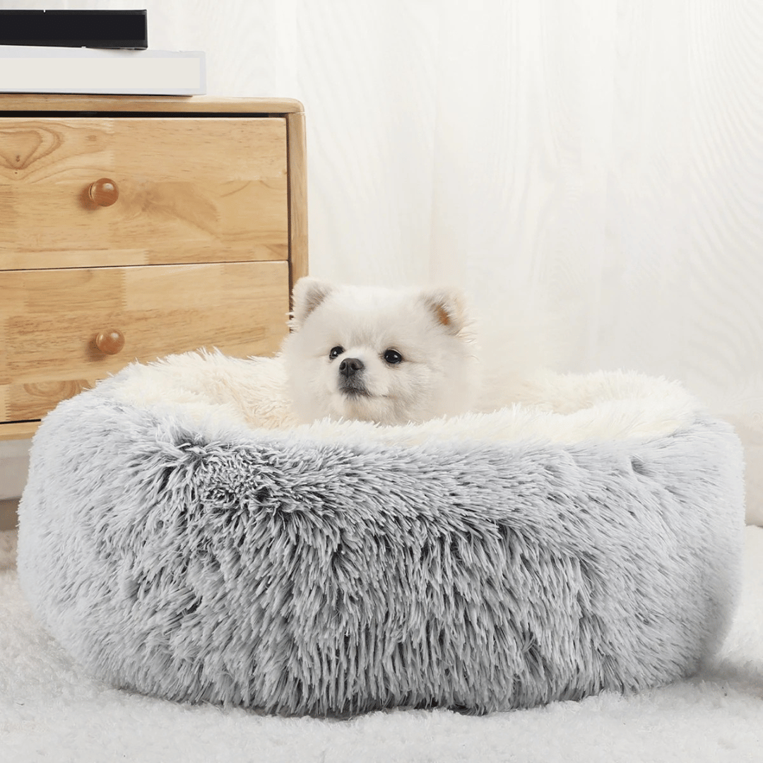 "Cozy plush donut dog bed with deep sides, faux fur, circular shape for comfort and anxiety relief in various sizes."
