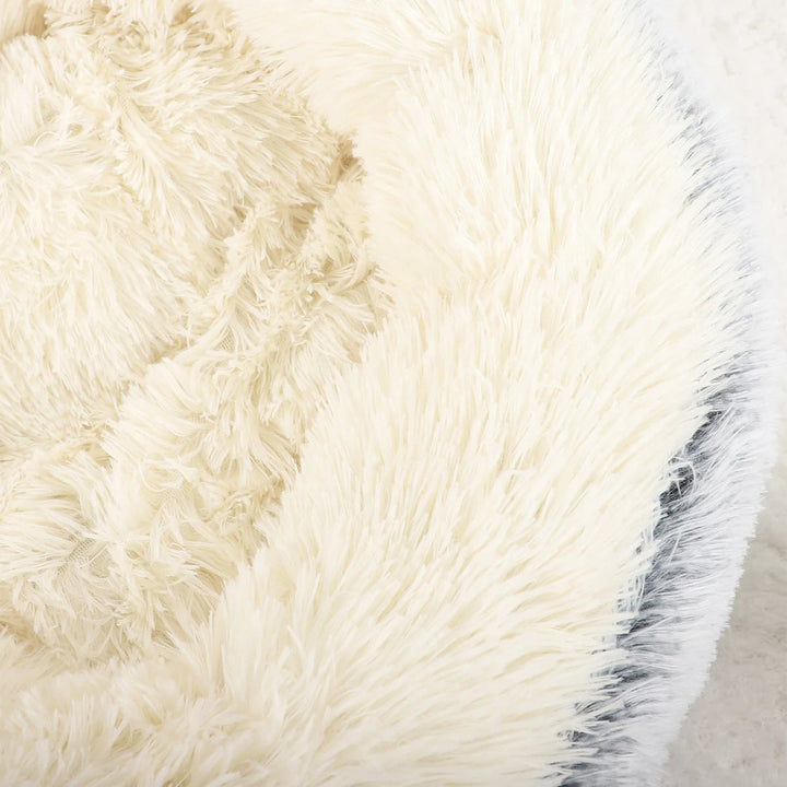 "Cozy plush donut dog bed with deep sides, faux fur, circular shape for comfort and anxiety relief in various sizes."