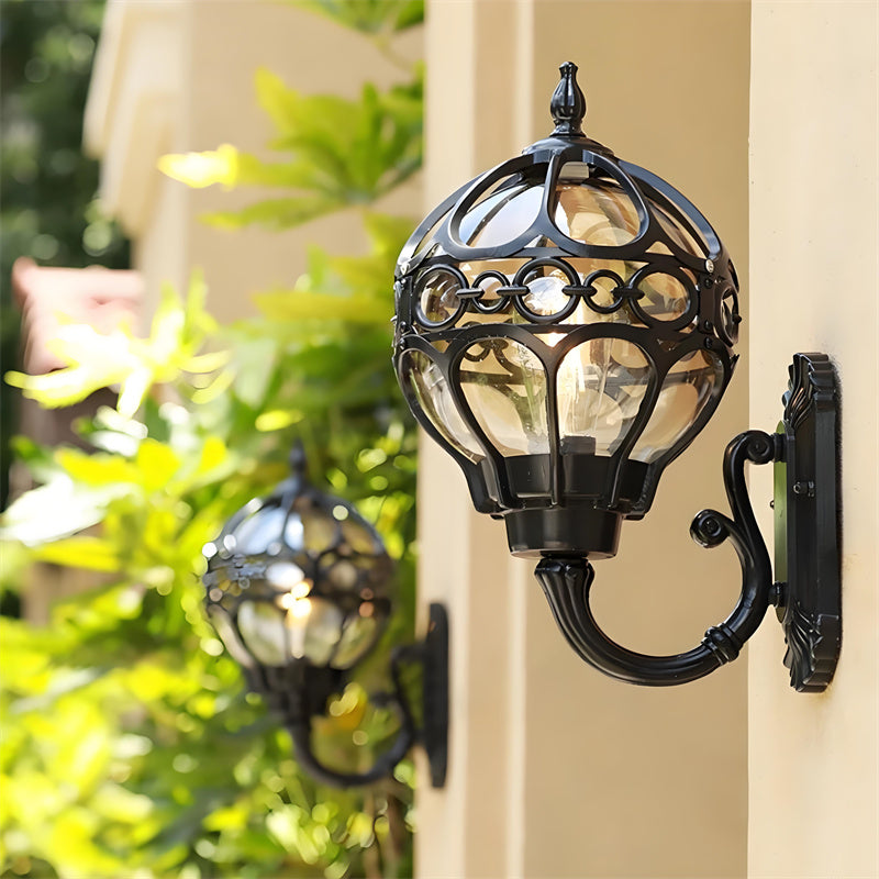 "Elegant bronze/black outdoor wall light with matte finish, transparent globe shade, perfect for garden or porch lighting."