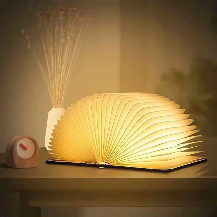 "Elegant foldable LED book lamp, warm white light, 360-degree design, portable for home or travel, wood and paper material."