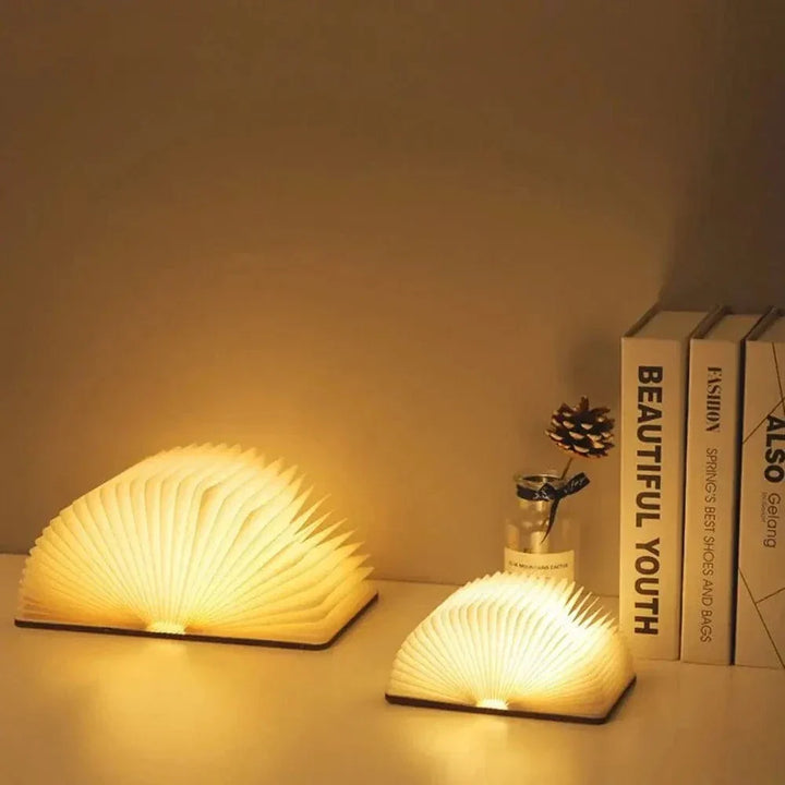 "Elegant foldable LED book lamp, warm white light, 360-degree design, portable for home or travel, wood and paper material."