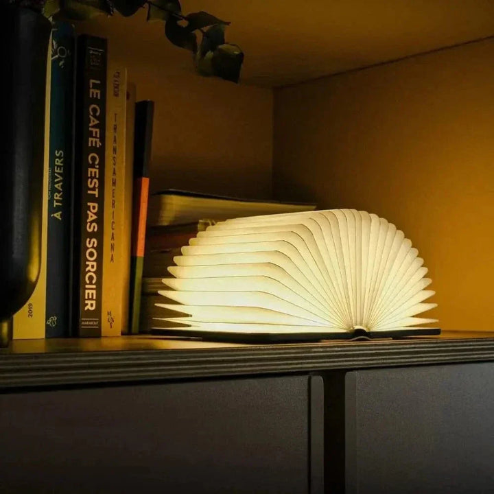 "Elegant foldable LED book lamp, warm white light, 360-degree design, portable for home or travel, wood and paper material."