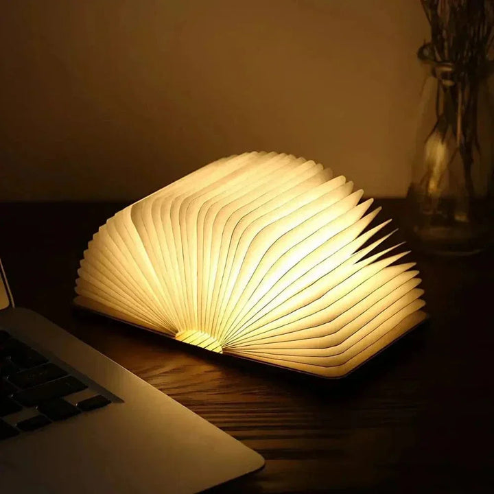 "Elegant foldable LED book lamp, warm white light, 360-degree design, portable for home or travel, wood and paper material."
