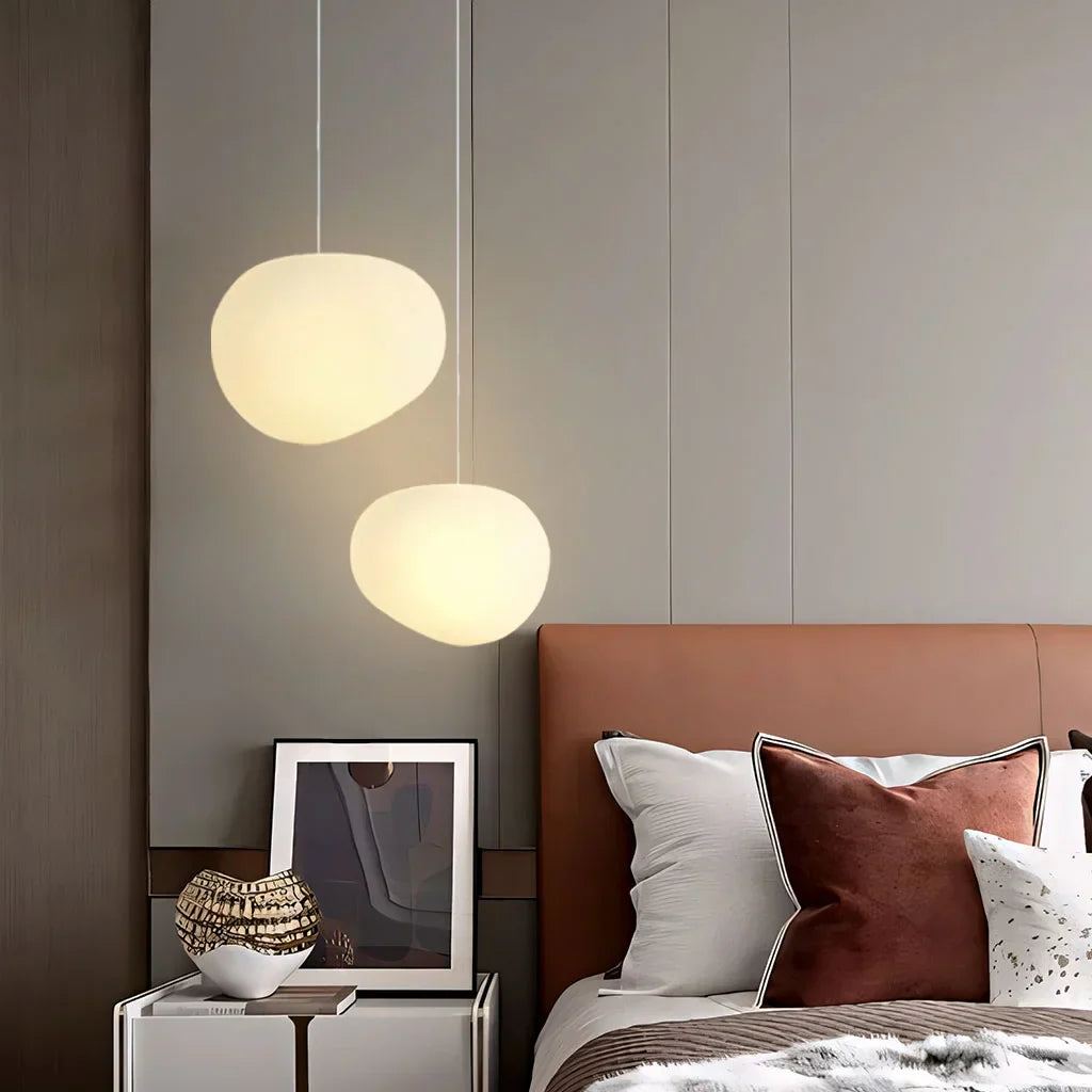 Elegant white pebble pendant light; minimal design, frosted glass, metal accents, soft glow for modern interiors.