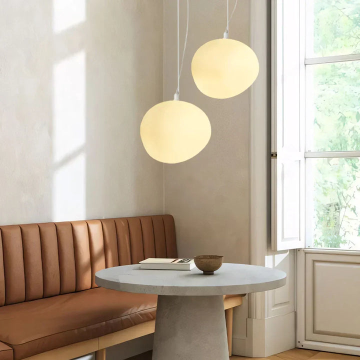 Elegant white pebble pendant light; minimal design, frosted glass, metal accents, soft glow for modern interiors.