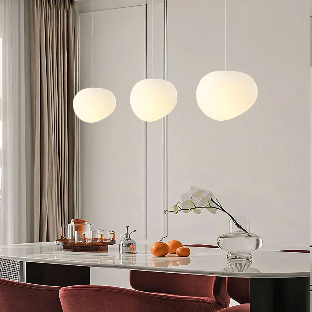 Elegant white pebble pendant light; minimal design, frosted glass, metal accents, soft glow for modern interiors.