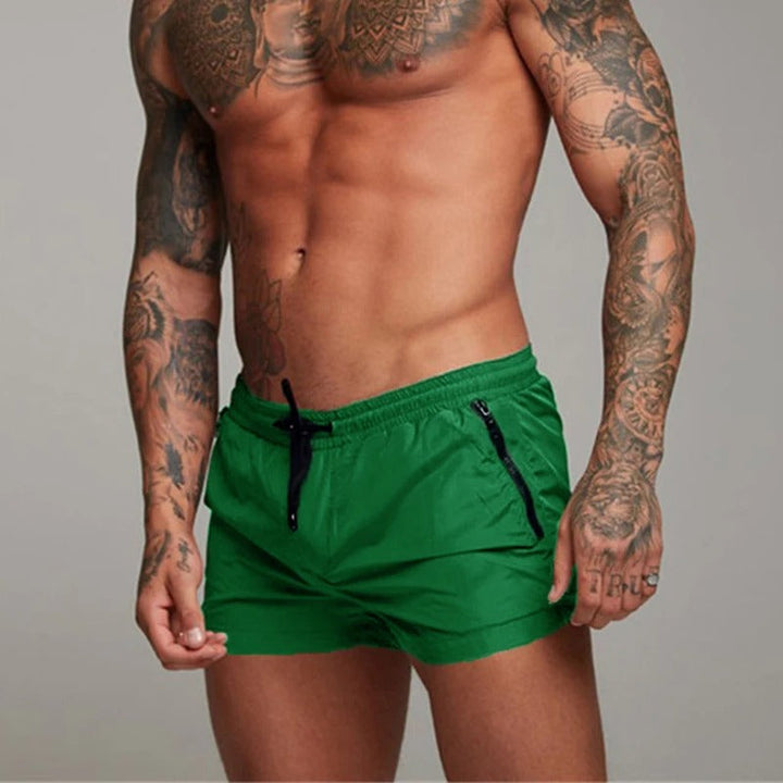 "Men's quick-dry, stretchy swim shorts with pockets in vibrant colors, featuring an elastic waistband and sleek design."