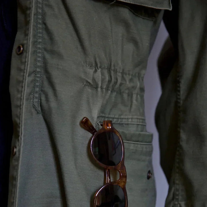 Men's vintage cotton field jacket with adjustable waist, rugged design, breathable fabric, suitable for layering.