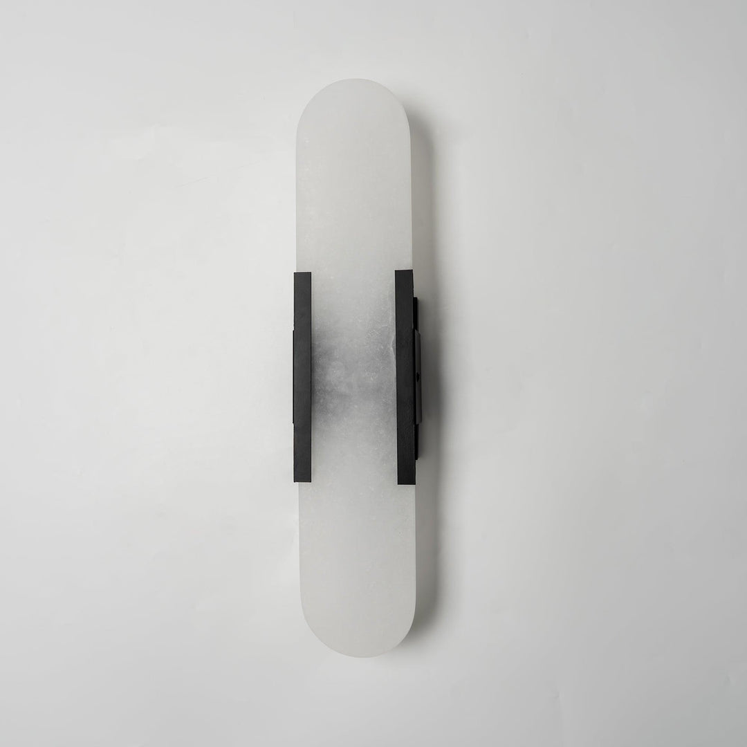 "Modern elongated alabaster wall lamp with metal and brass accents, emits warm glow, suitable for chic interior decor."